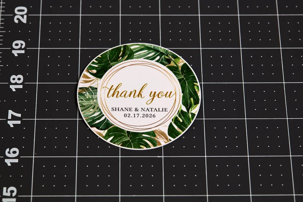 Round green leaf patterned sticker with 'thank you' text on a grid background